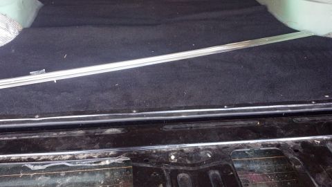 1995 Ford Bronco - The cargo area of a vehicle, showing the carpeted floor and metal trim pieces.