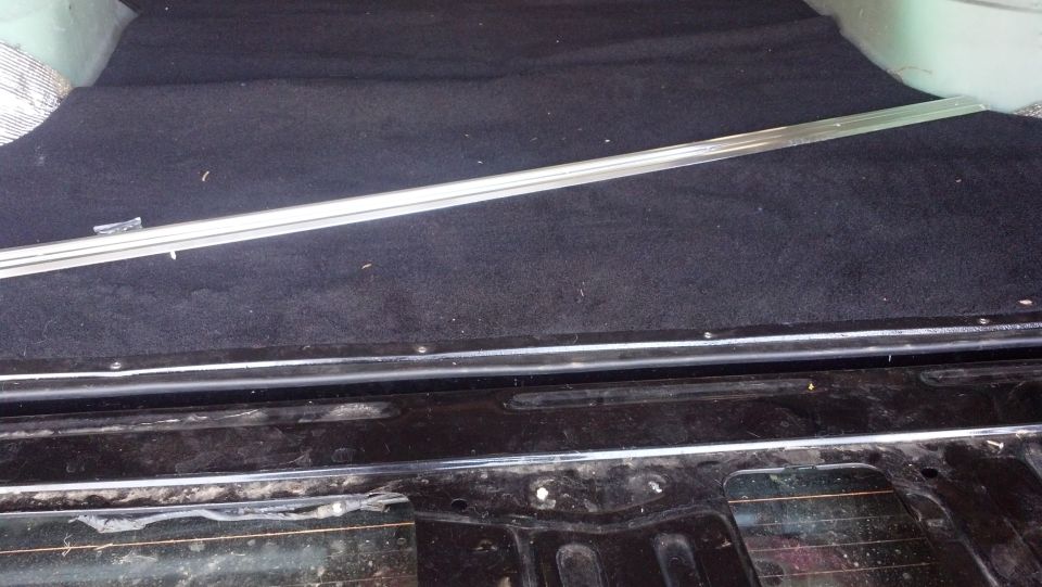 Interior cargo area with black carpet and a silver trim piece. The lower section shows black metal with chrome trim