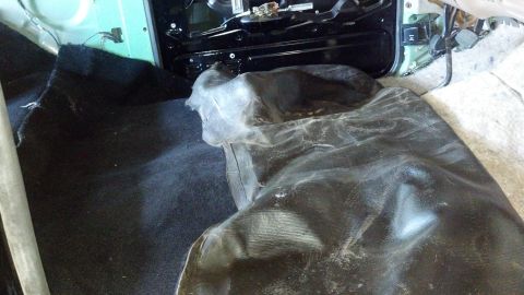 1995 Ford Bronco - The interior of a vehicle is shown with the floor carpet and seat mechanism exposed, covered by a protective mat.