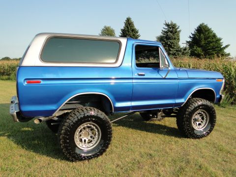 1978 Ford Bronco - This lifted 1978 Ford Bronco, painted in a vibrant blue with a silver top, is shown from a 3/4 front angle.