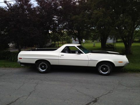 1972 Ford Ranchero - A white 1972 Ford Ranchero is parked on a residential street with trees and a house in the background.