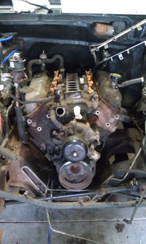 1993 Ford Bronco - The engine compartment of a vehicle is shown with various components exposed and disconnected.
