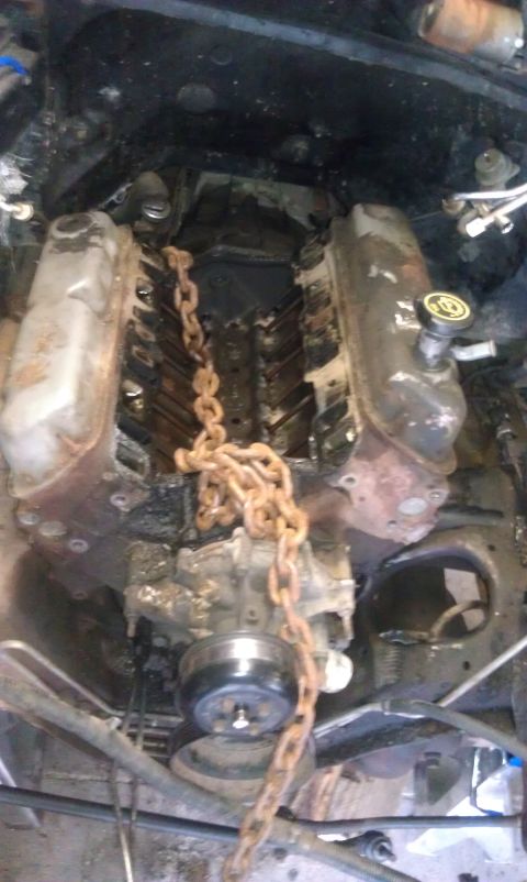1993 Ford Bronco - Engine block with a chain wrapped around it, undergoing some mechanical work.