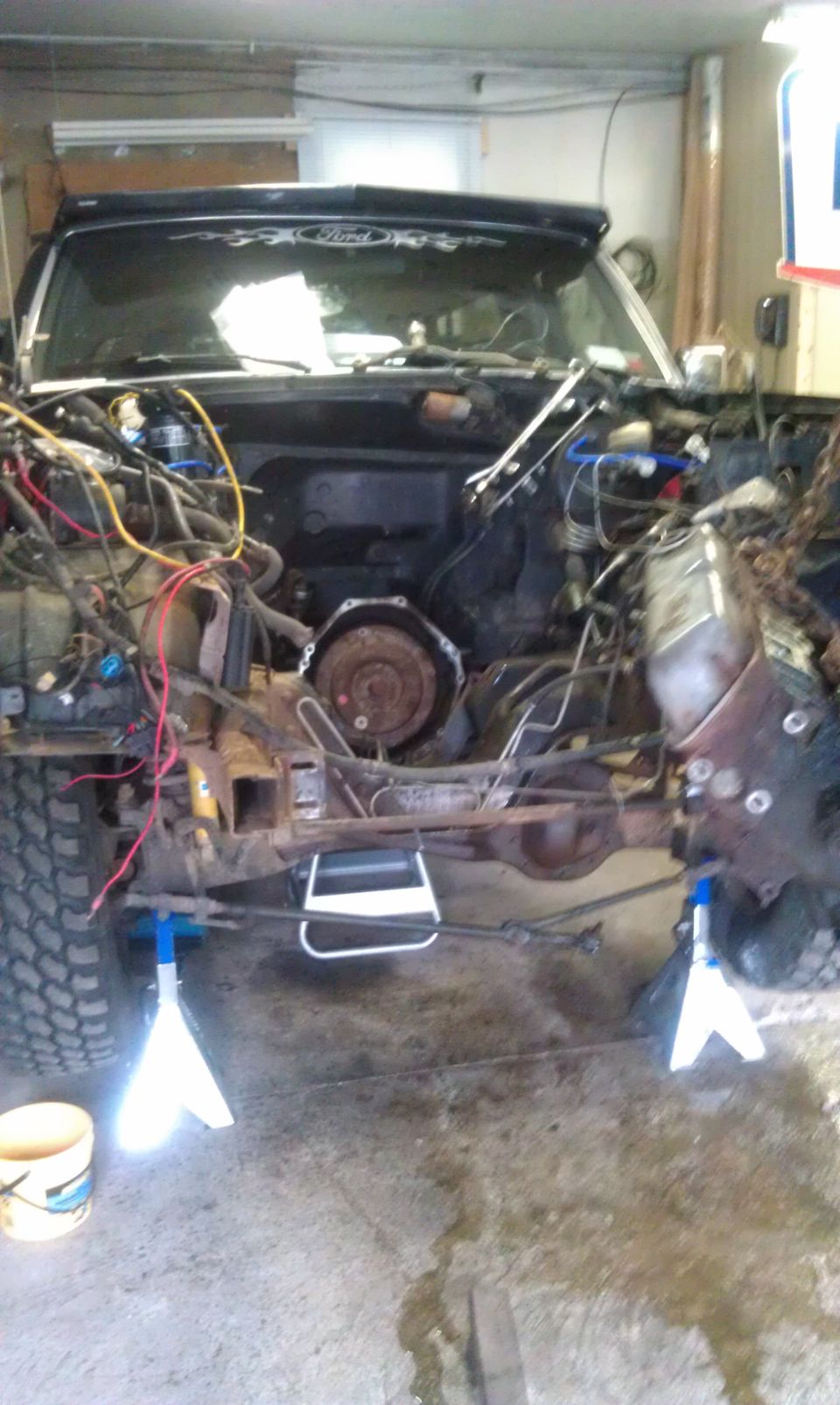 1993 Ford Bronco front end disassembled on jack stands, engine bay exposed