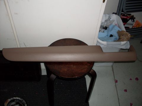 1996 Ford Bronco - A tan interior trim piece is displayed on a wooden stool in front of a white door and a trash can.