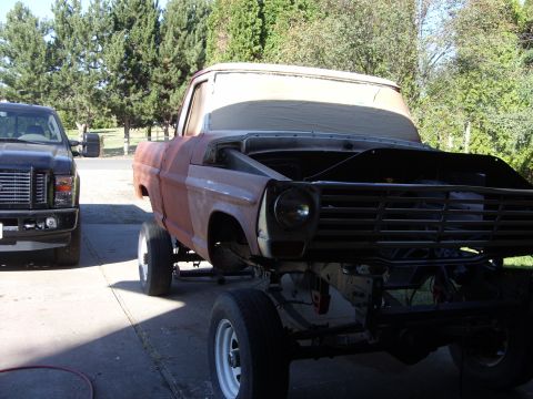 1967 Ford F-250 - A rusty 1967 Ford F-250 pickup truck sits in a driveway next to a newer black truck.