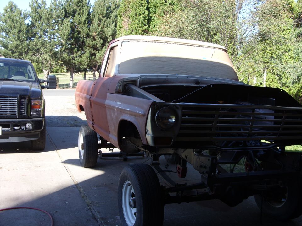 Rusty 1967 Ford F-250 pickup truck, front view, hood open, undergoing restoration