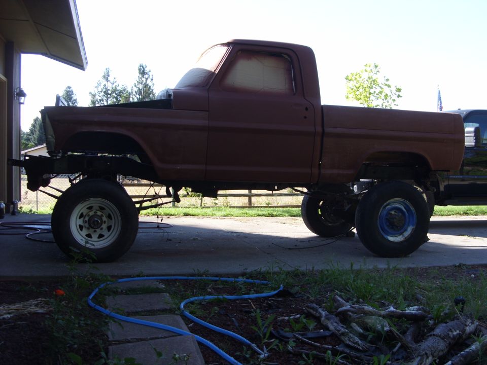 1967 Ford F-250 pickup truck, side view, undergoing restoration with exposed frame and raised suspension