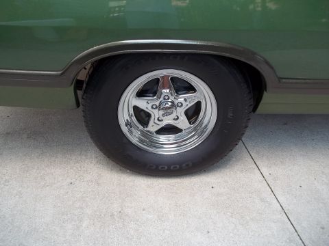 1970 Ford Ranchero - Close-up of a vehicle's rear wheel a chrome star rim and a Goodyear tire against a concrete surface.