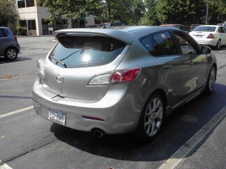 2010 Mazda 3 - Rear view of a silver Mazda 3 hatchback parked in a lot with other vehicles.