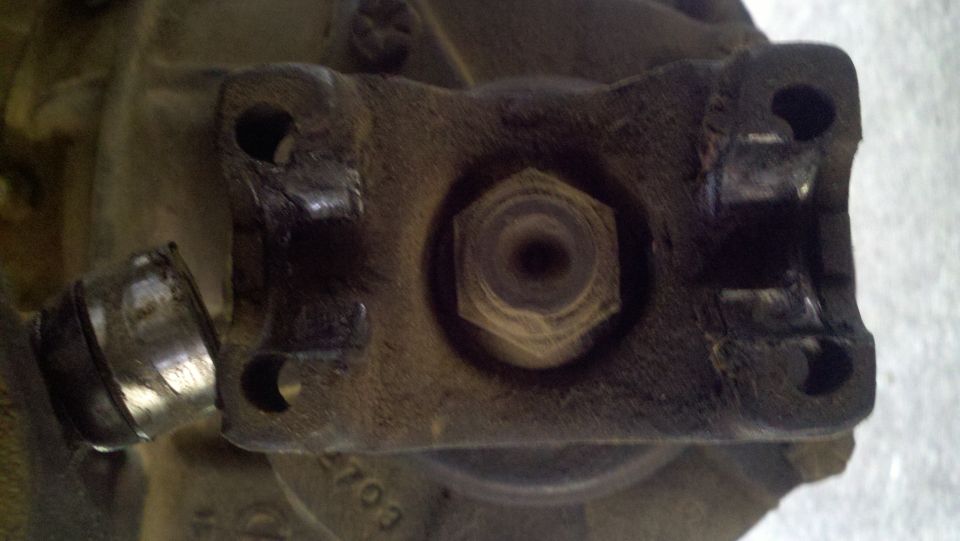 Close-up of a driveshaft U-joint with some wear and tear. There's a hex bolt in the center