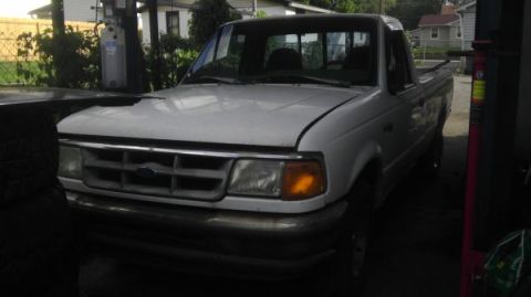 1987 Ford Ranger - A white Ford pickup truck is parked indoors, with its hood open, revealing the front grille and headlights.