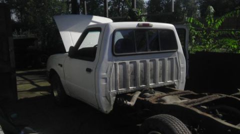 1987 Ford Ranger - Pickup truck chassis, likely a Ford Ranger, with the hood up and rear bed removed.