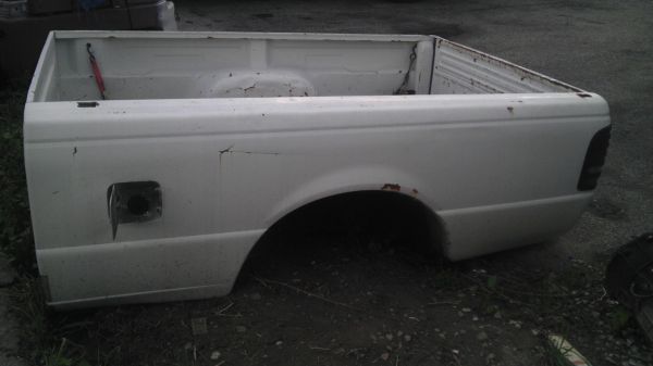 White pickup truck bed, side view, showing fuel door and wheel well