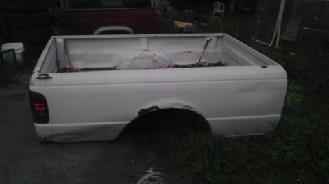 1987 Ford Ranger - A white pickup truck bed sits in a grassy area, showing signs of rust and wear.