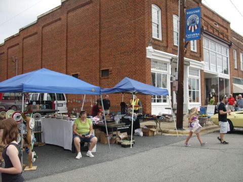 2012 Ford Bronco - A street fair is underway with vendors displaying goods under tents, while pedestrians stroll by.