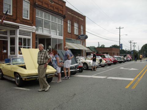 2012 Ford Bronco - A line of classic cars are displayed on a street in front of brick buildings.