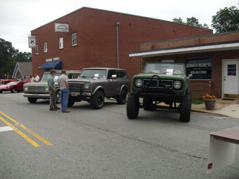 2012 Ford Bronco - Several SUVs are parked on the street in front of a brick building with businesses.