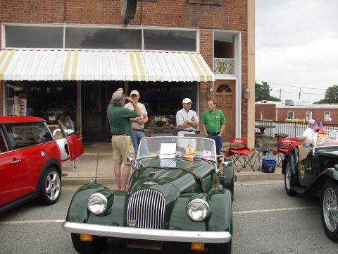 2012 Ford Bronco - Several people stand around a classic green convertible parked in front of a brick building.