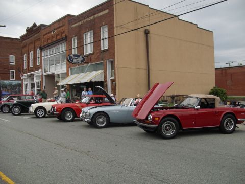 2012 Ford Bronco - Classic cars lined up on a street, with one red convertible's hood open.