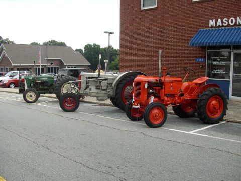 2012 Ford Bronco - Three vintage tractors are parked in a row outside a building with a "MASON" sign.