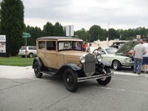 2012 Ford Bronco - A vintage tan and black sedan is parked on the street, with other vehicles and people around.