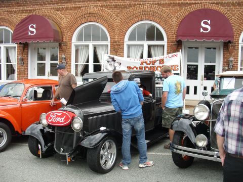 2012 Ford Bronco - A black Ford car is displayed with its hood up, drawing attention from onlookers.