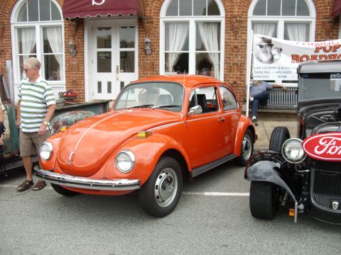 2012 Ford Bronco - An orange Volkswagen Beetle is parked alongside a Ford hot rod at an outdoor event.