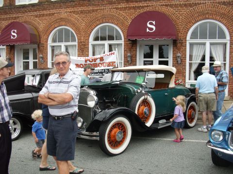 2012 Ford Bronco - People gather around a vintage green convertible with distinctive orange wheels at an outdoor event.