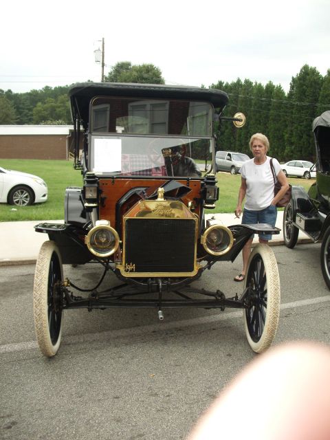 2012 Ford Bronco - A woman stands next to a vintage 1914 Ford Model T automobile parked outdoors.