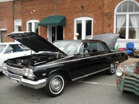 2012 Ford Bronco - A black 1962 Chevrolet Impala coupe is displayed with its hood and trunk open, alongside other vehicles.