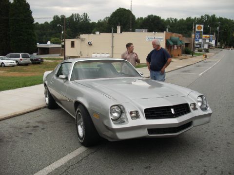 2012 Ford Bronco - A silver coupe is parked on the side of the road with two men standing nearby.