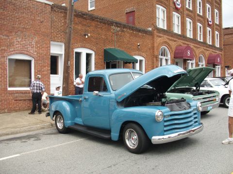 2012 Ford Bronco - Two pickup trucks and a car are parked in front of a brick building.