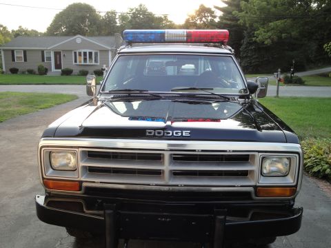 1987 Dodge 1500 - Frontal view of a black 1987 Dodge 1500 police truck equipped with a red and blue light bar.