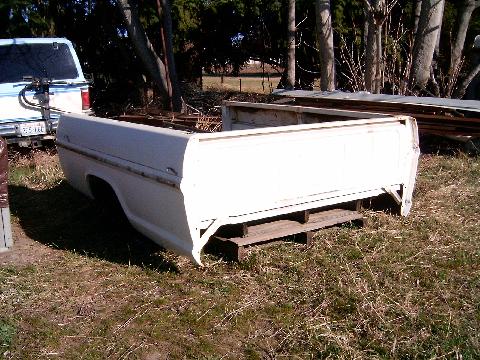 1967 Ford F-250 - A white 1967 Ford F-250 truck bed is shown from the rear, resting on pallets in a grassy area.