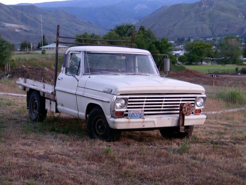 1967 Ford F-250 - This 1967 Ford F-250 flatbed truck is parked in a grassy field with mountains visible behind it.