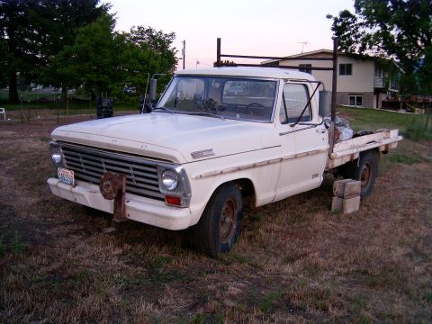 1967 Ford F-250 - A white 1967 Ford F-250 truck with a flatbed is parked outdoors on a dry, grassy area.