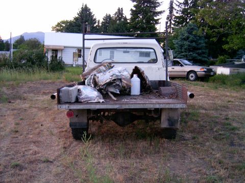 1967 Ford F-250 - Pickup truck bed loaded with junk, with a second vehicle visible in the background.