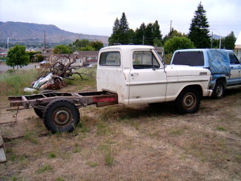 1967 Ford F-250 - This 1967 Ford F-250 chassis is parked next to another vehicle in a rural setting.