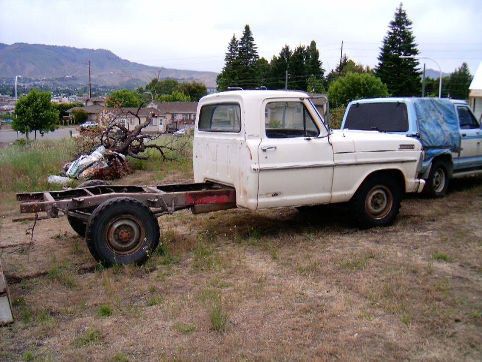 White 1967 Ford F-250 chassis, side view, parked in a grassy lot