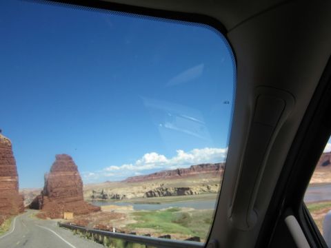 1991 Ford LTD Crown Victoria - Driving through a picturesque landscape with towering red rock formations and a calm body of water under a clear blue sky.