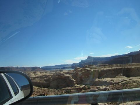 1991 Ford LTD Crown Victoria - A scenic drive through a desert landscape with layered rock formations and a distant body of water.