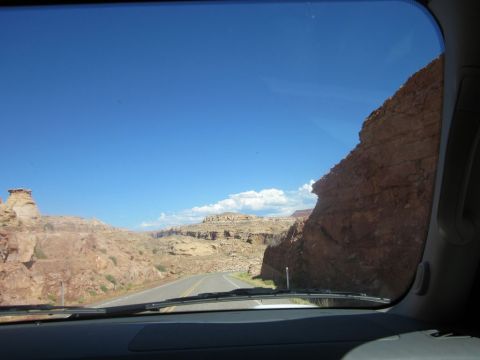 1991 Ford LTD Crown Victoria - A road travels through the desert landscape of Monument Valley, with towering rock formations on either side.