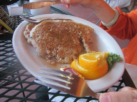 1991 Ford LTD Crown Victoria - A plate of pancakes with orange slices and butter is ready to be eaten at an outdoor table.