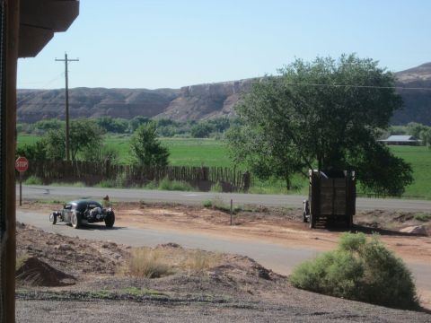 1991 Ford LTD Crown Victoria - A hot rod and a truck are seen on a road in a rural landscape. The Supermotors logo is in the corner.