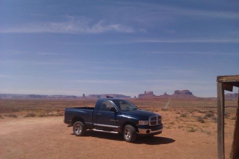 1991 Ford LTD Crown Victoria - A blue pickup truck is parked in the desert landscape of Monument Valley under a clear blue sky.