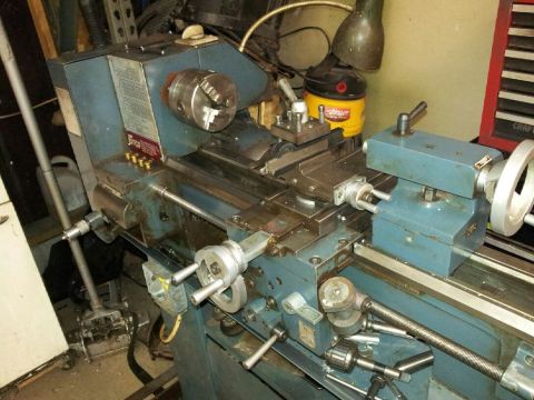 1989 Ford Bronco - A blue metal lathe is shown in a cluttered workshop environment with various tools and equipment visible.