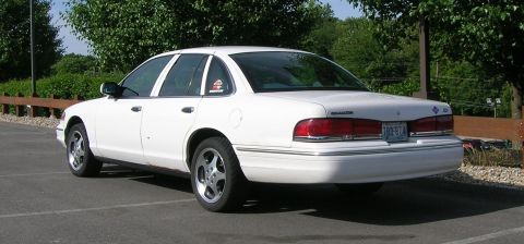 2004 Ford Crown Victoria - A white sedan is parked in an outdoor lot, showing its rear and side profile.