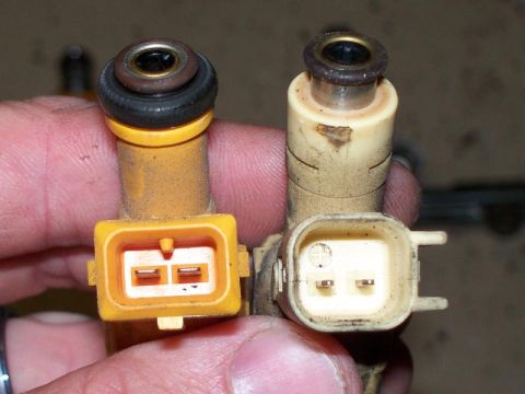 1990 Ford Bronco - Close-up view of two fuel injectors, highlighting their connectors and top seals.