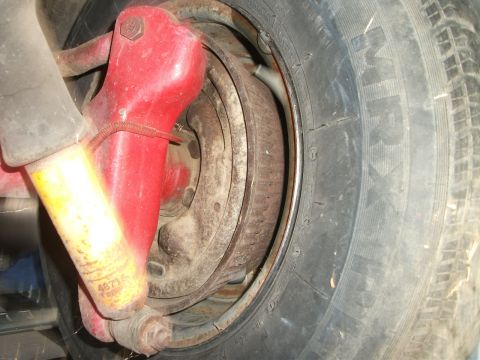 1972 Ford Ranchero - Close-up of a vehicle's wheel brake assembly, showing a red caliper and yellow shock absorber.